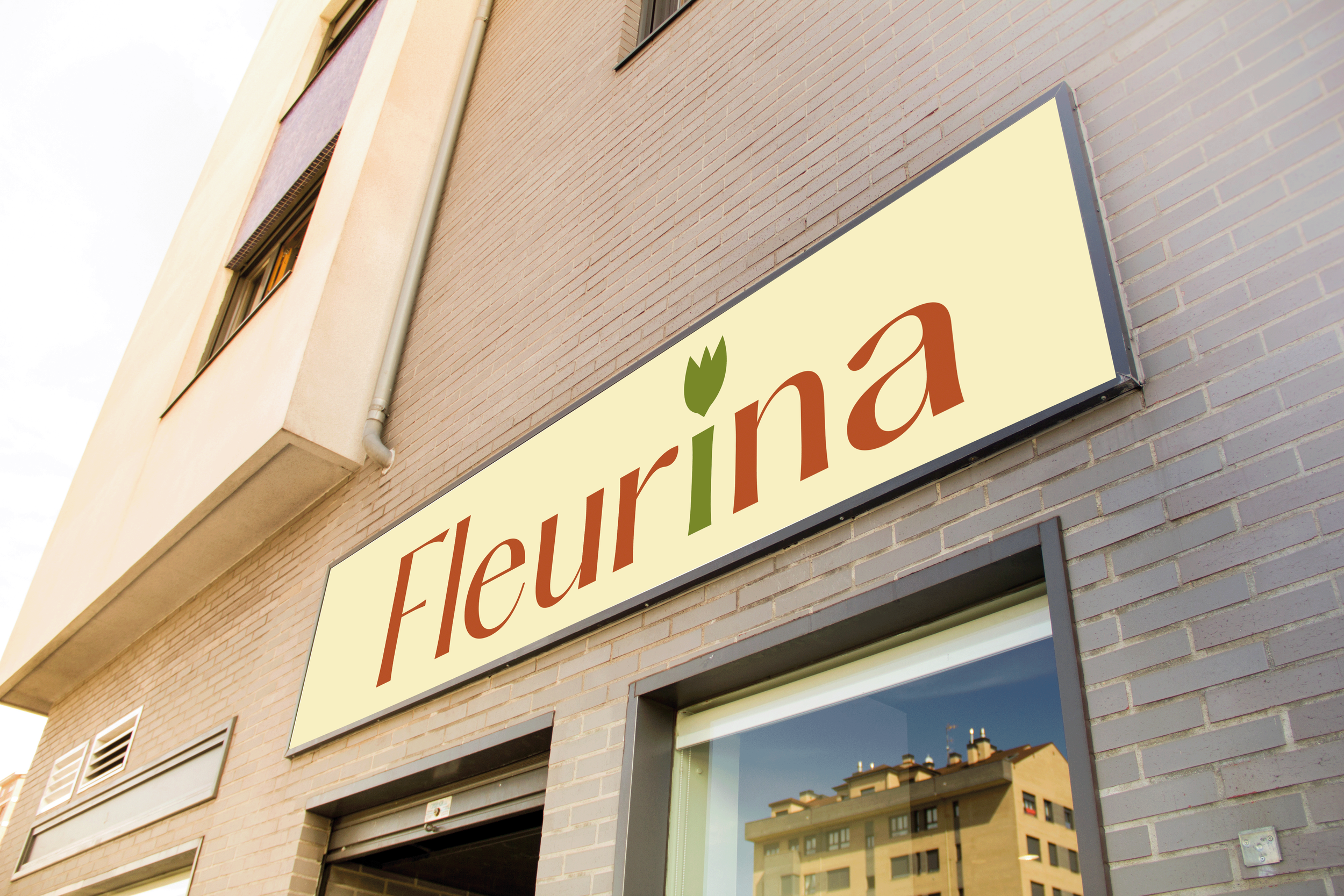 Une enseigne en façade d'un bâtiment avec le logo et le nom 'Fleurína' écrit en brun, avec une feuille verte stylisée en remplacement du point sur la lettre 'i'.