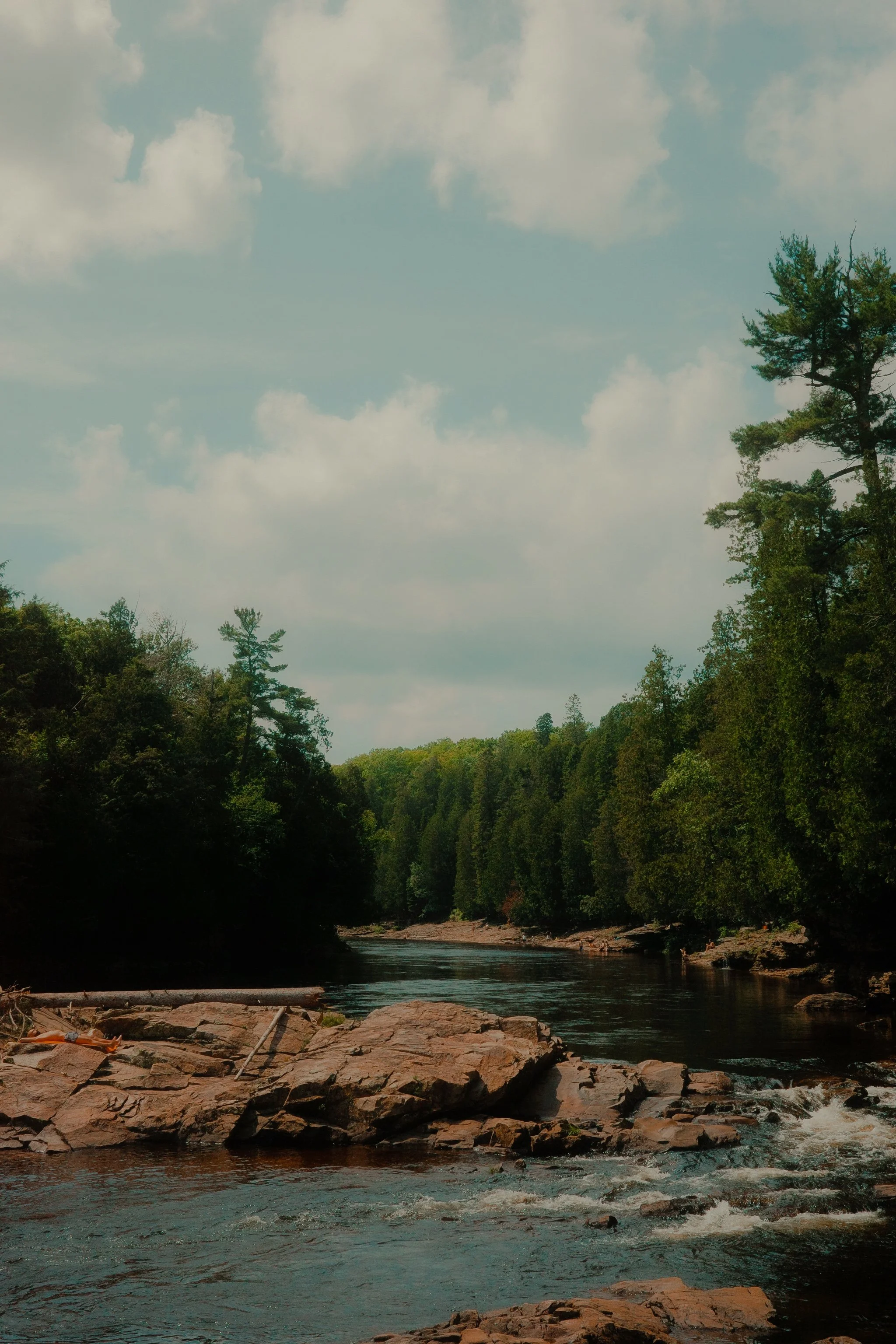 Une rivière entourée de forêts avec un ciel nuageux.