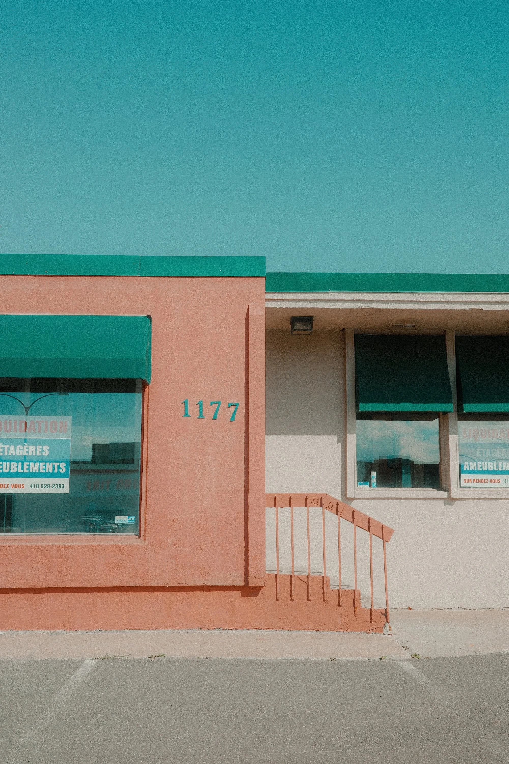 Façade d'un bâtiment avec le numéro 1177 et des fenêtres avec des affiches publicitaires.
