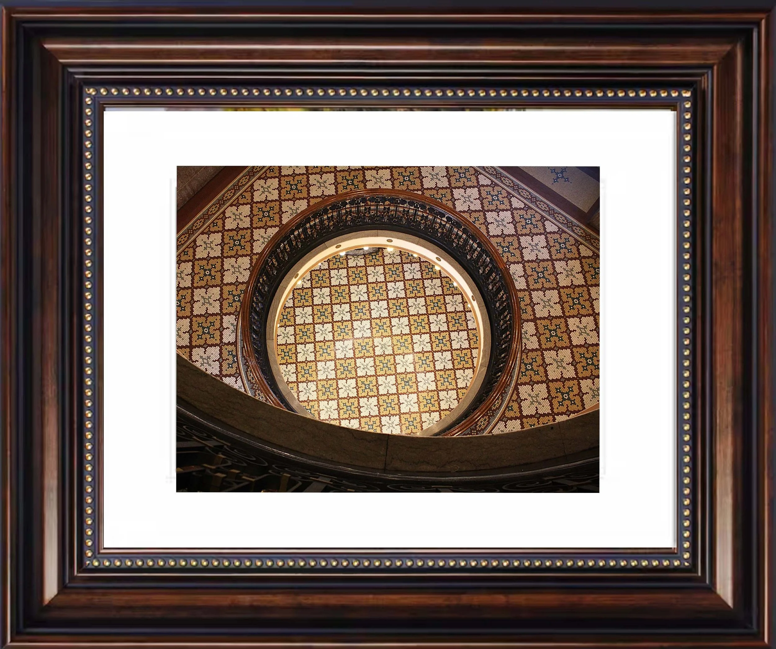 Looking down a spiral staircase with ornate tile flooring and wooden framing.