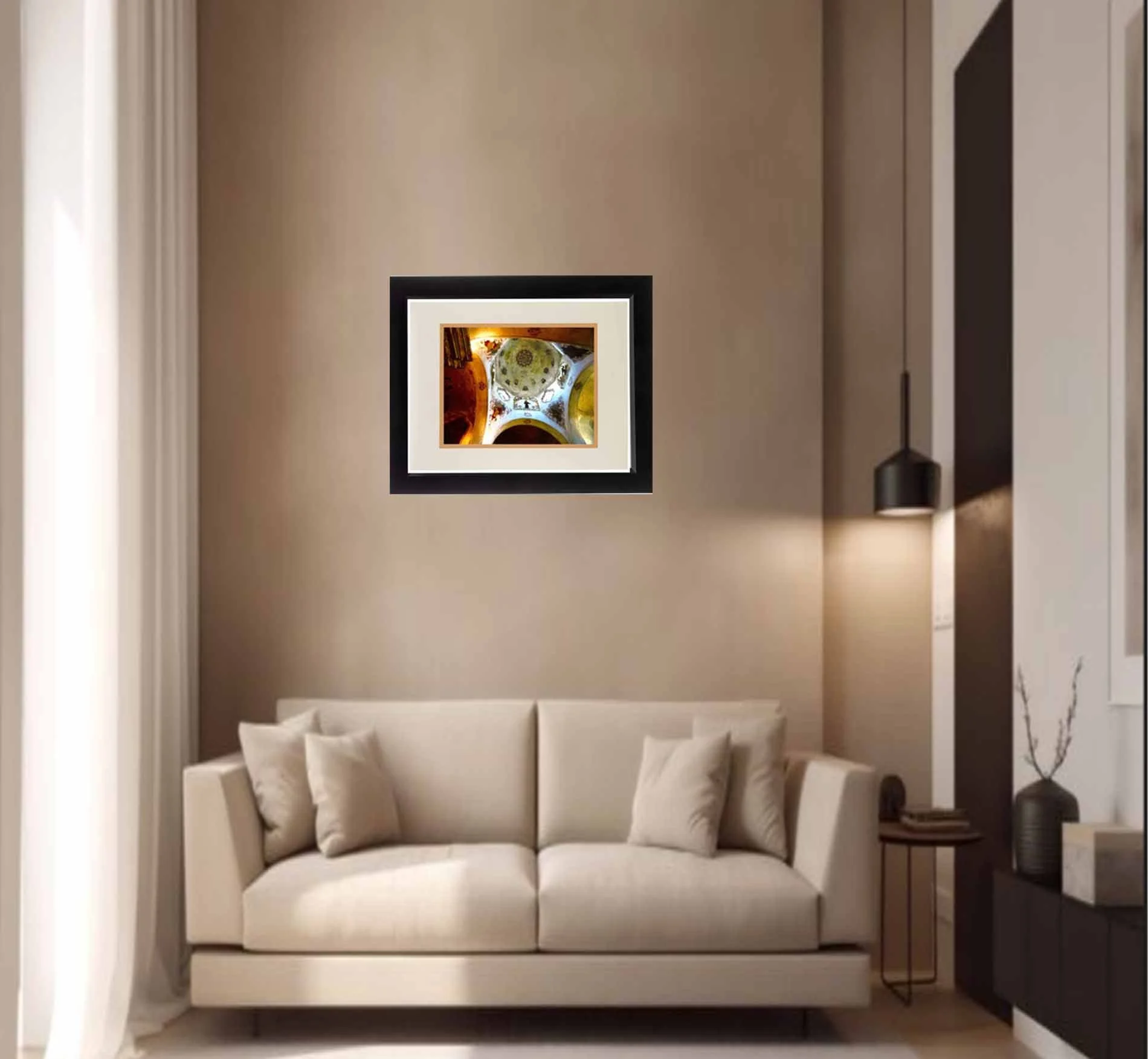 Modern living room with white sofa, framed artwork on beige wall, dark side table with a stack of books, and a black floor lamp.