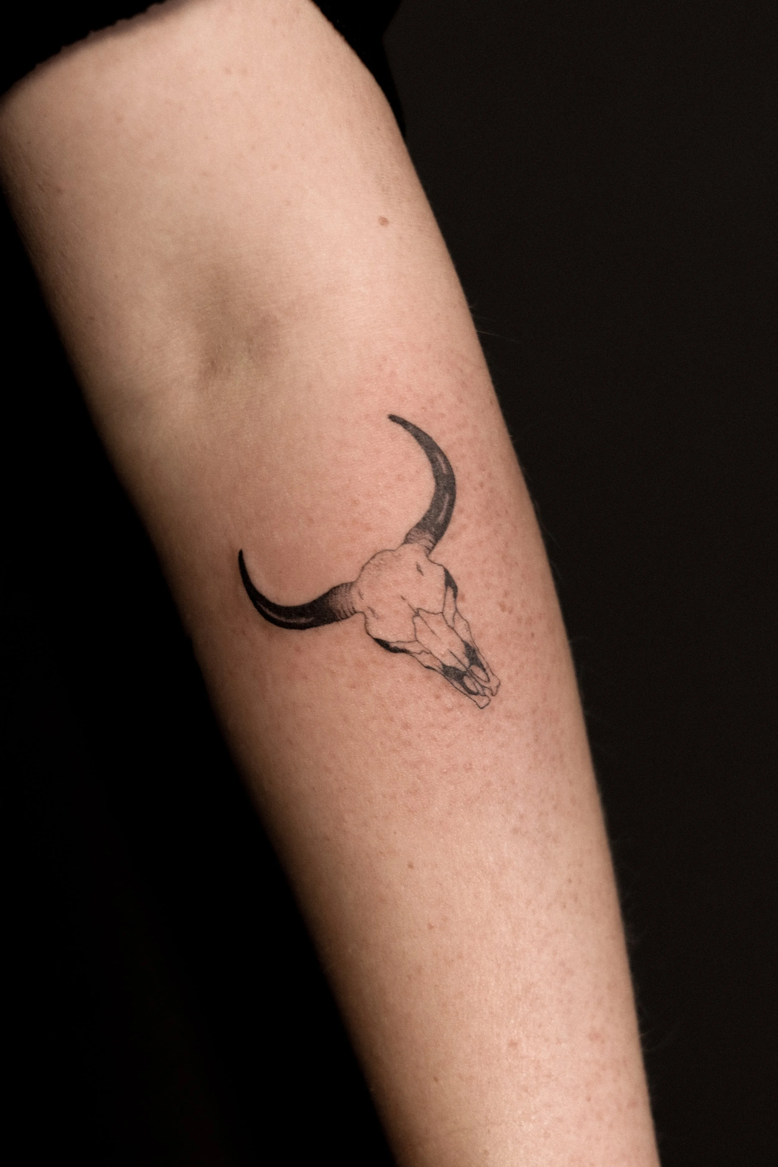 Tattoo van een ramshoorn en schedel op menselijke arm