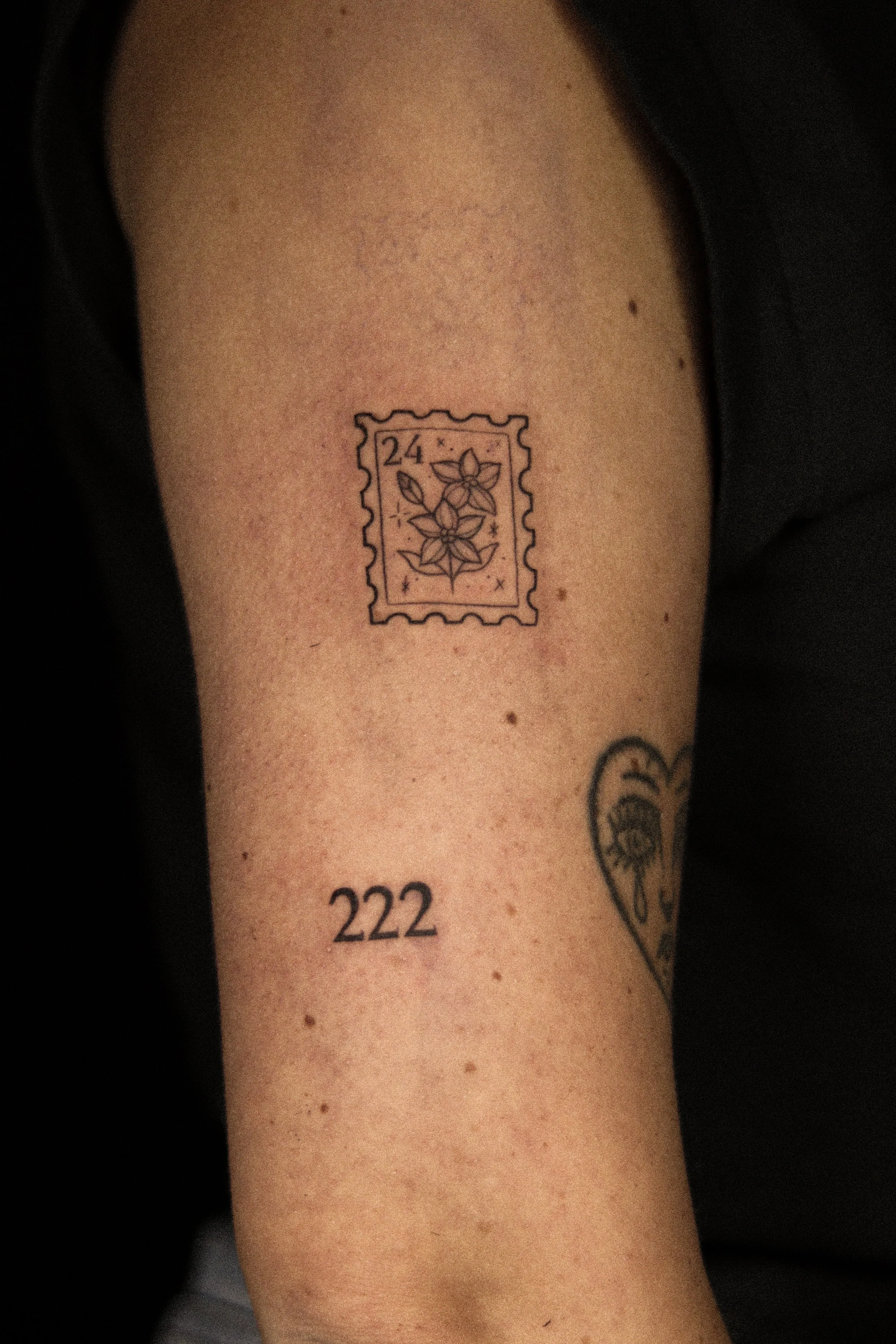 Tattoo van een gestempeld postzegel met bloemen en de tekst '24 x'.