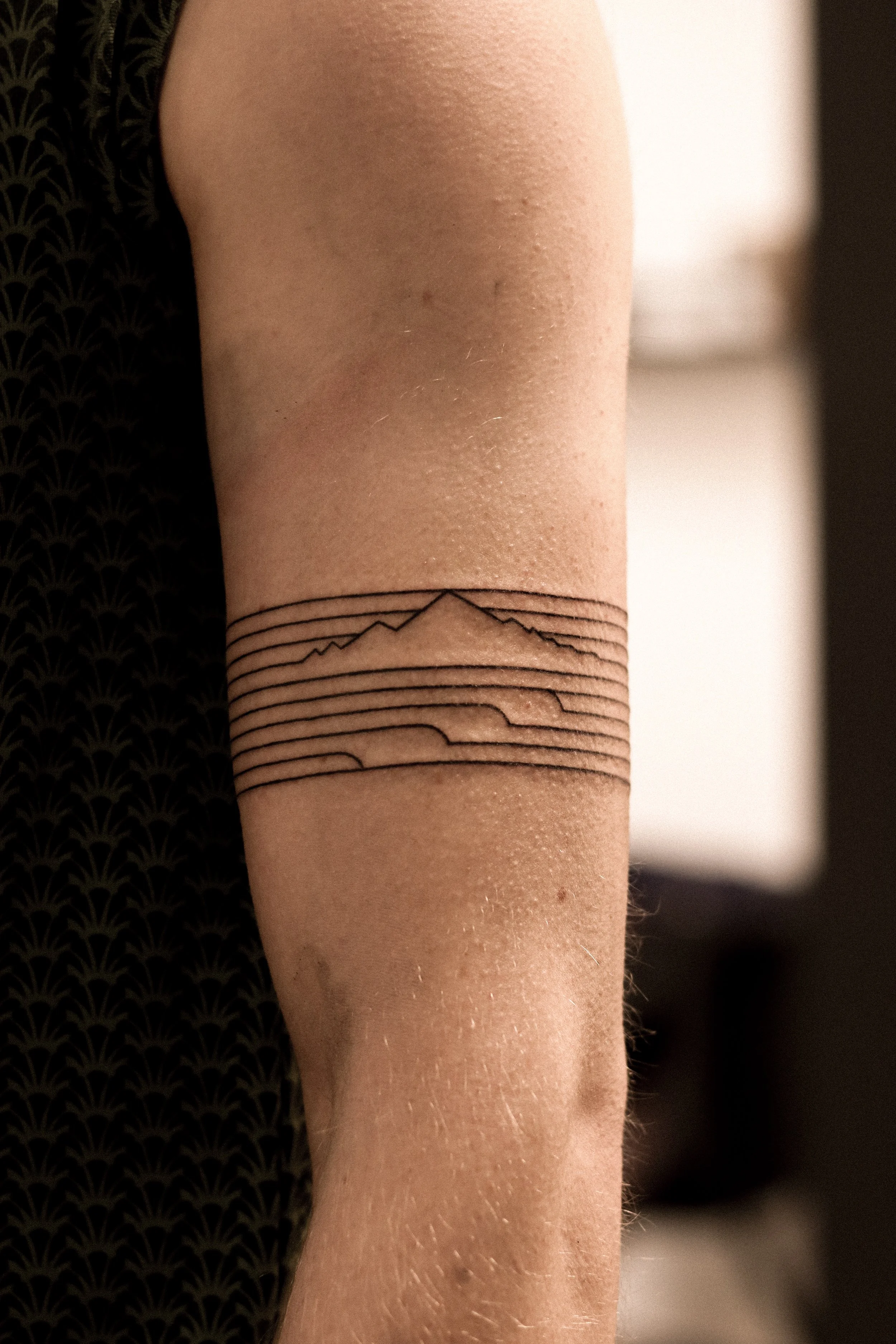 Tatoeage van een berg en golven op de arm.