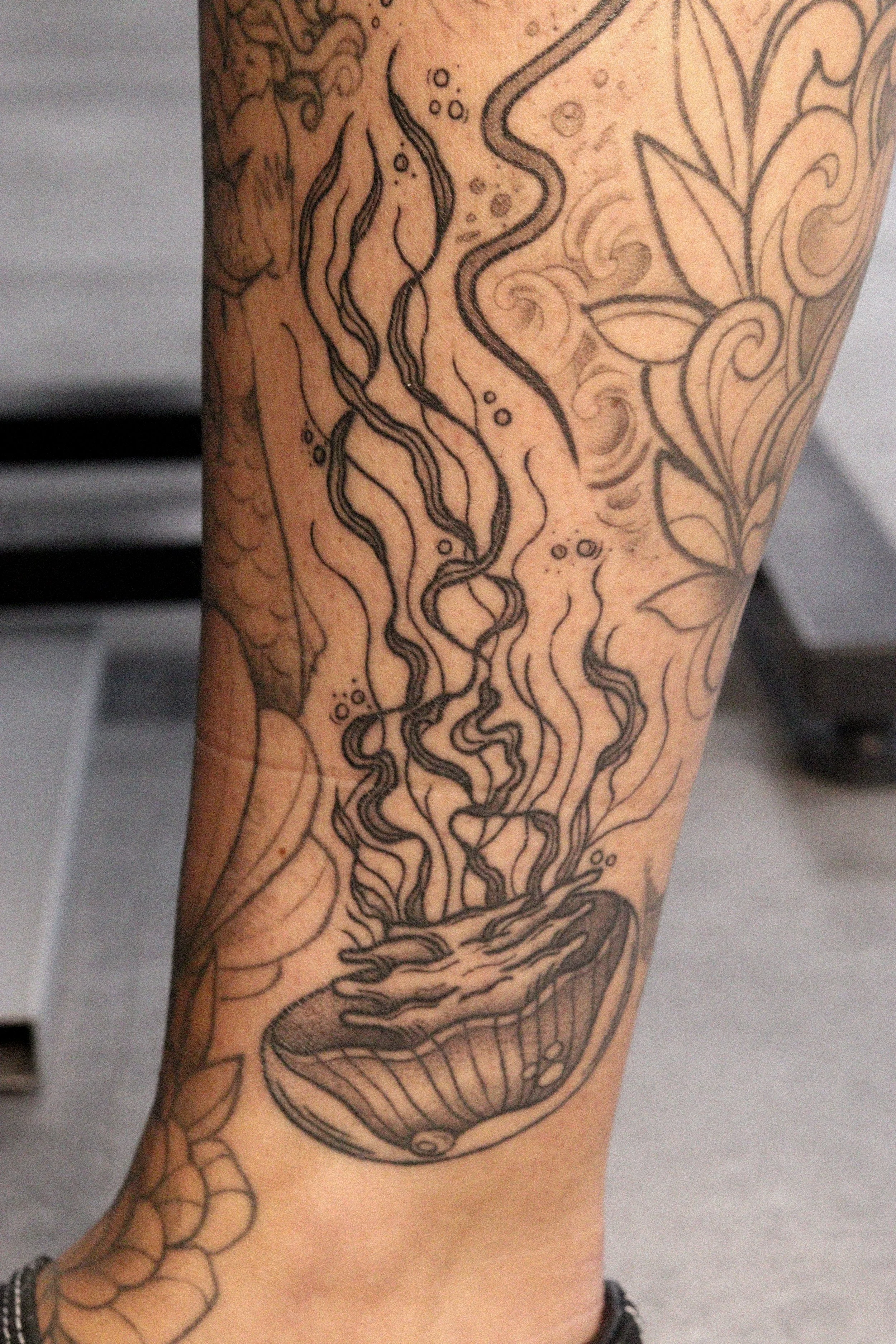 Tatoeage van een kom, waarvan de inhoud opwarmt en rook opstijgt, omgeven door bloemen en bladeren.