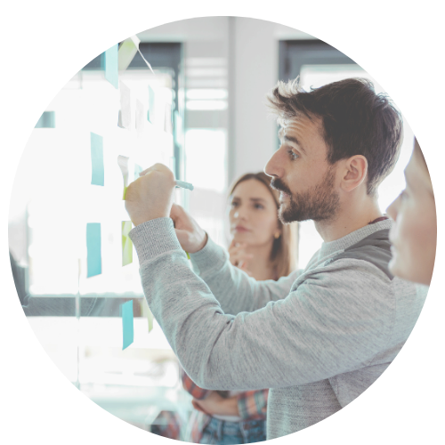 Kolmas ihminen kirjoittaa värilliselle viivakoodiheijastimelle ja keskustelee kahden muun ihmisen kanssa luokkahuoneessa, jossa on valkoisia seinäpapereita ja ikkunat taustalla.