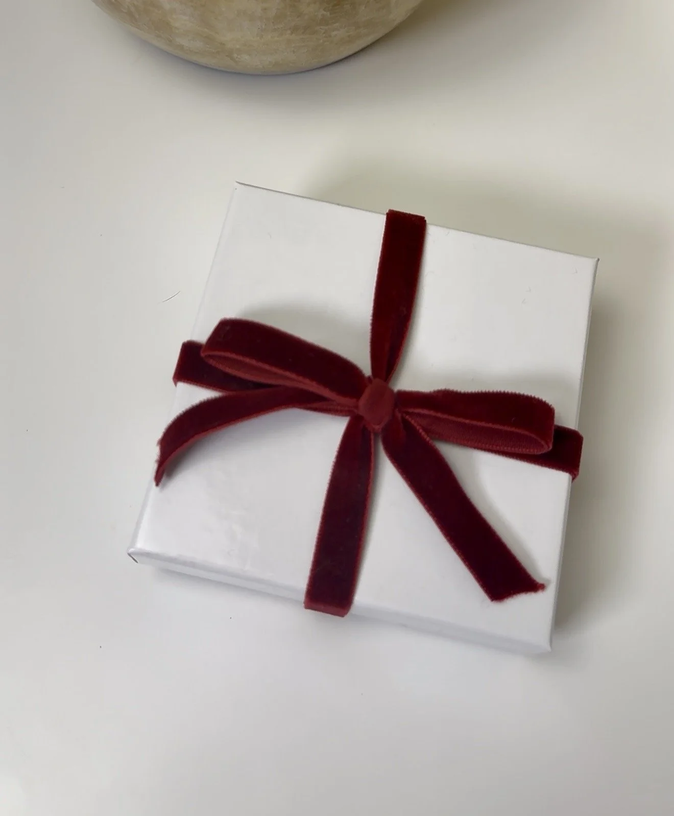 image of studio hill designs product packaging with white box and red velvet ribbon.