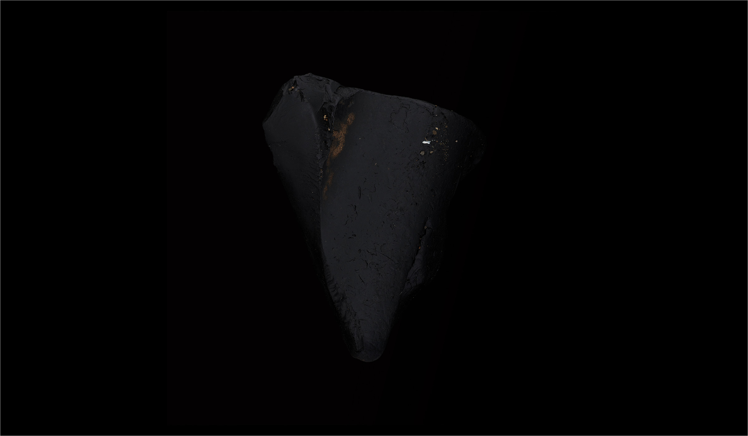 A black obsidian arrowhead against a black background.