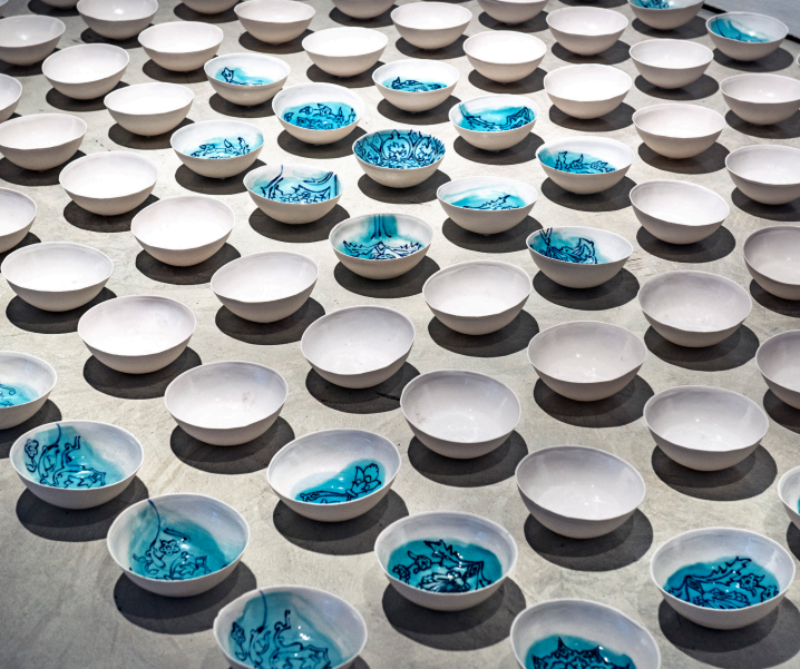 An array of white ceramic bowls arranged on a flat surface, some with blue decorative patterns inside.
