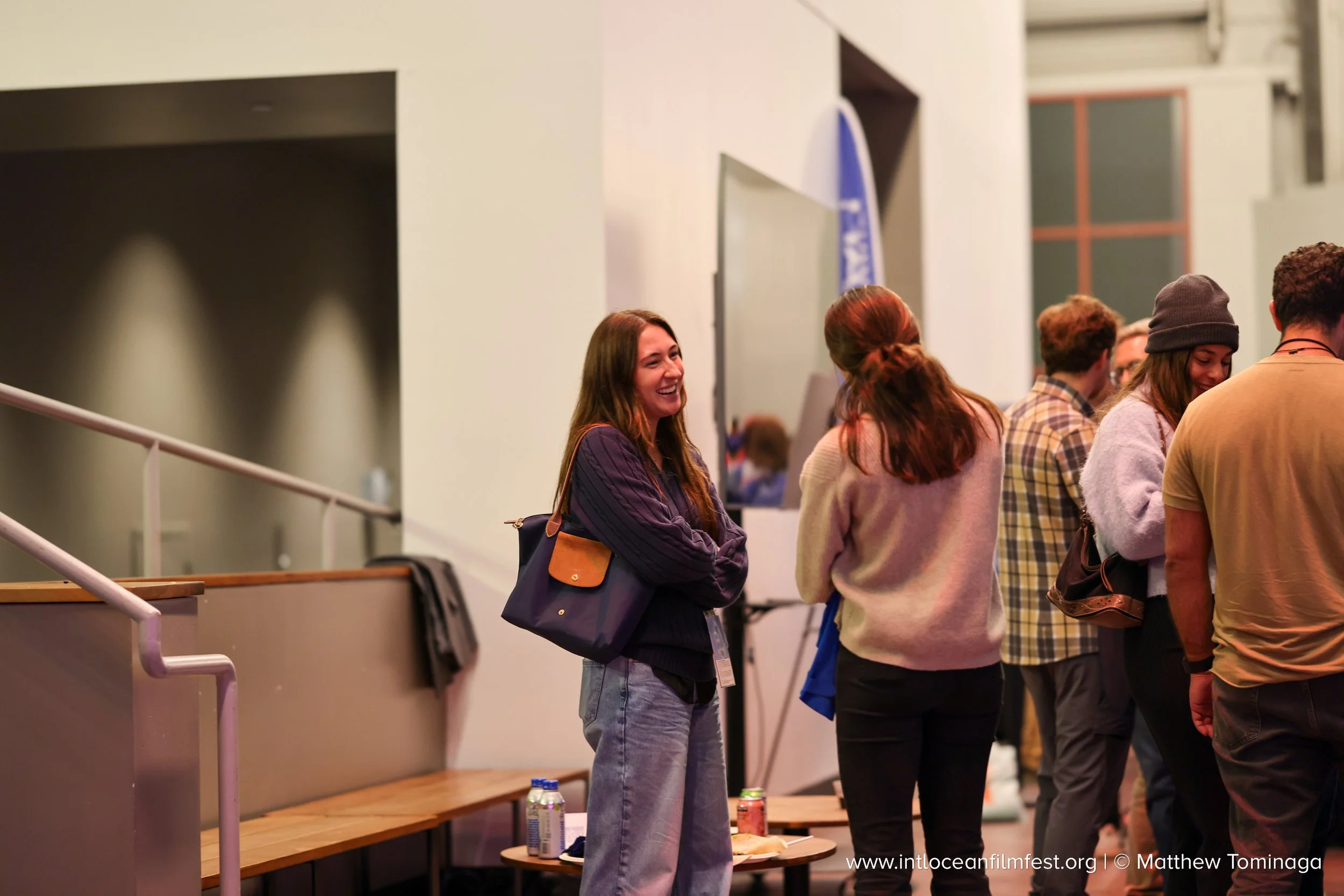 Group of young people waiting in line at an indoor event, smiling and conversing.