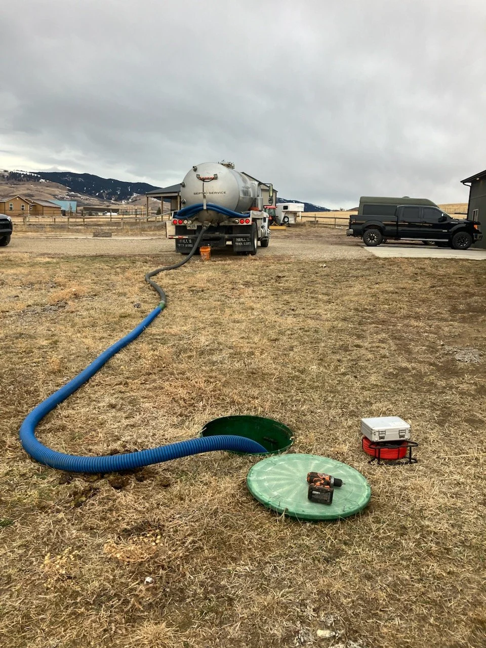Septic truck pumping a tank with the mountains in the background