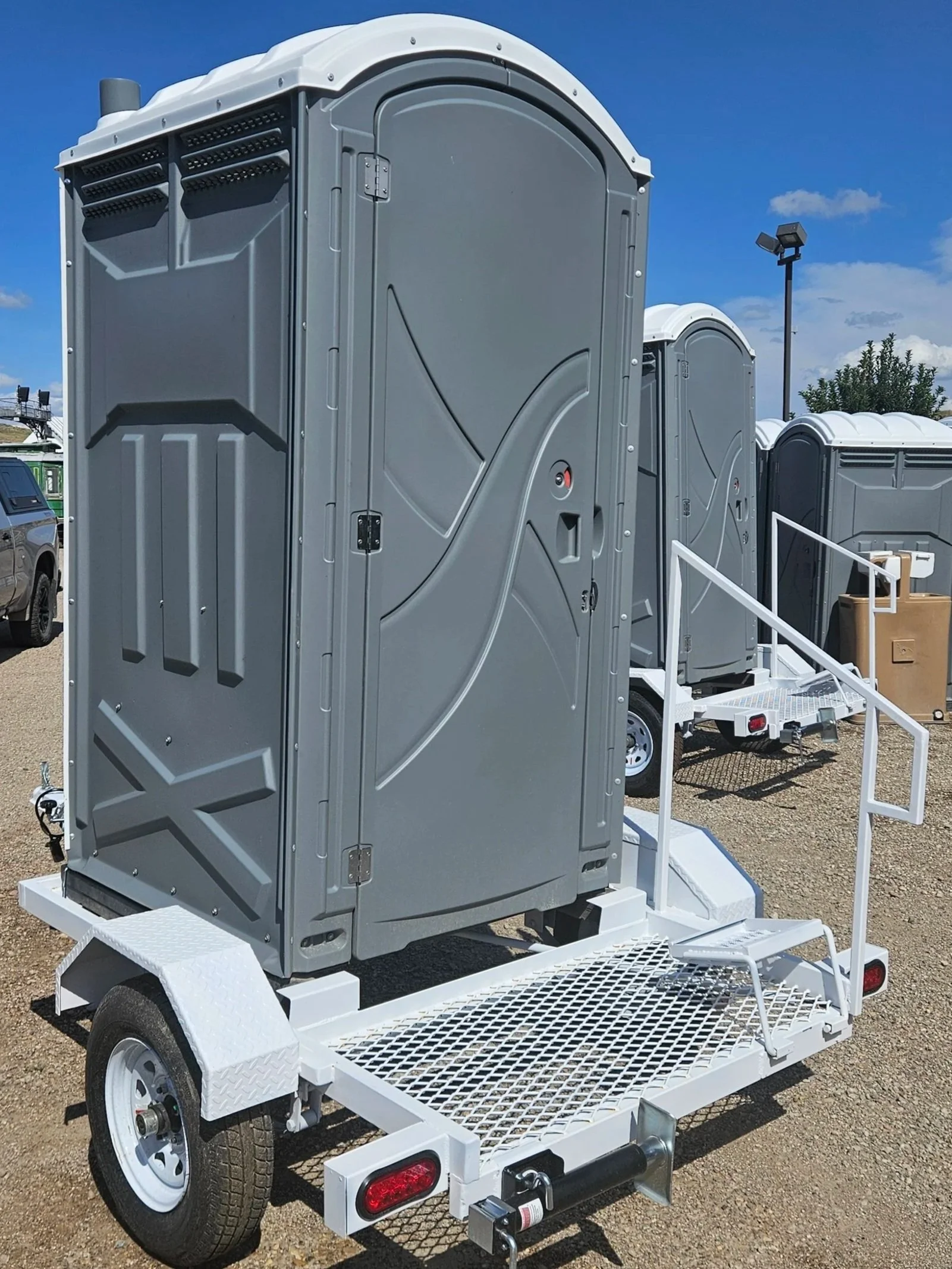 Grey porta potty mounted on trailer