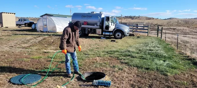A man working a jetting into a line with the pump truck in the background.