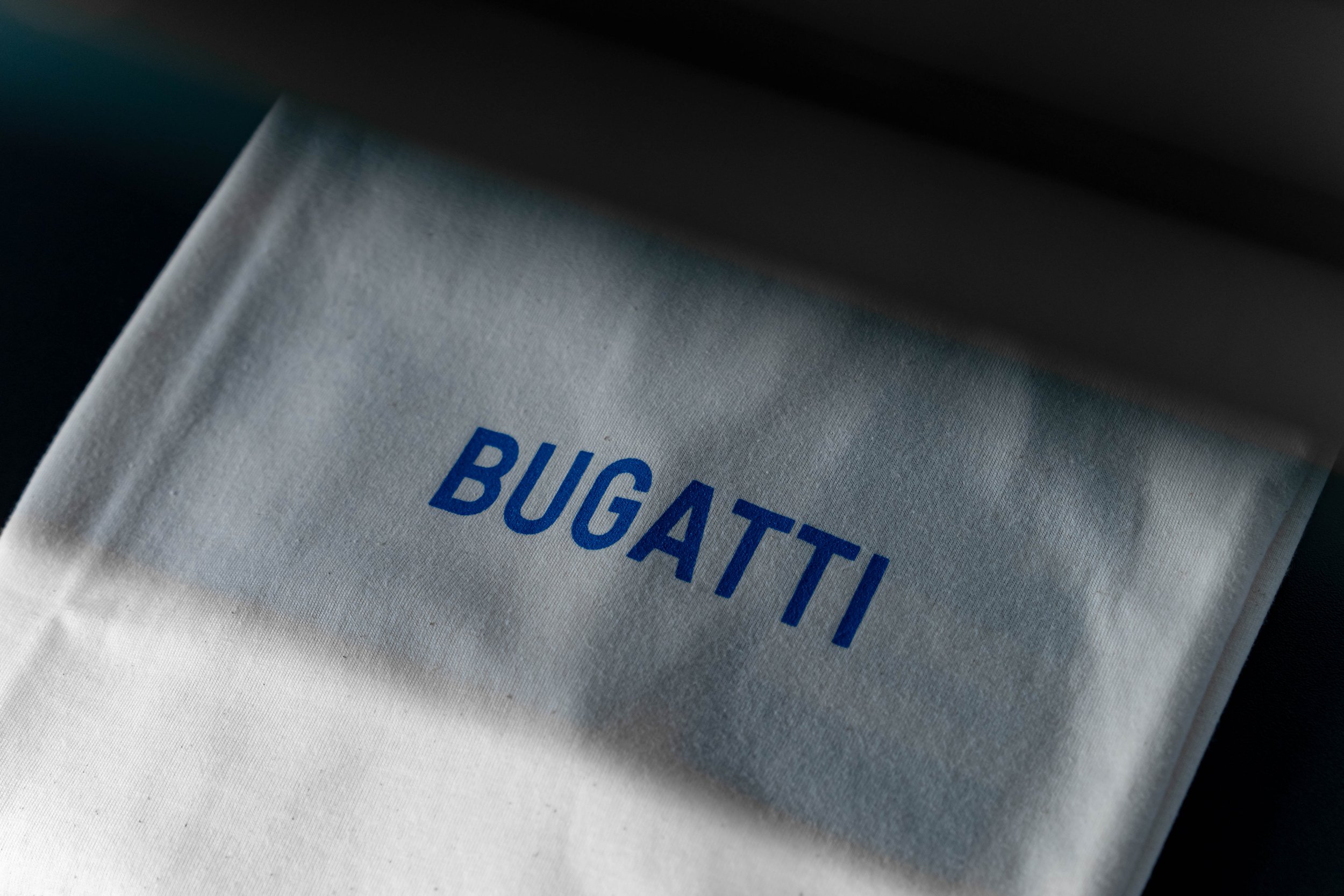 Close-up of a white fabric with the blue word 'BUGATTI' printed on it.