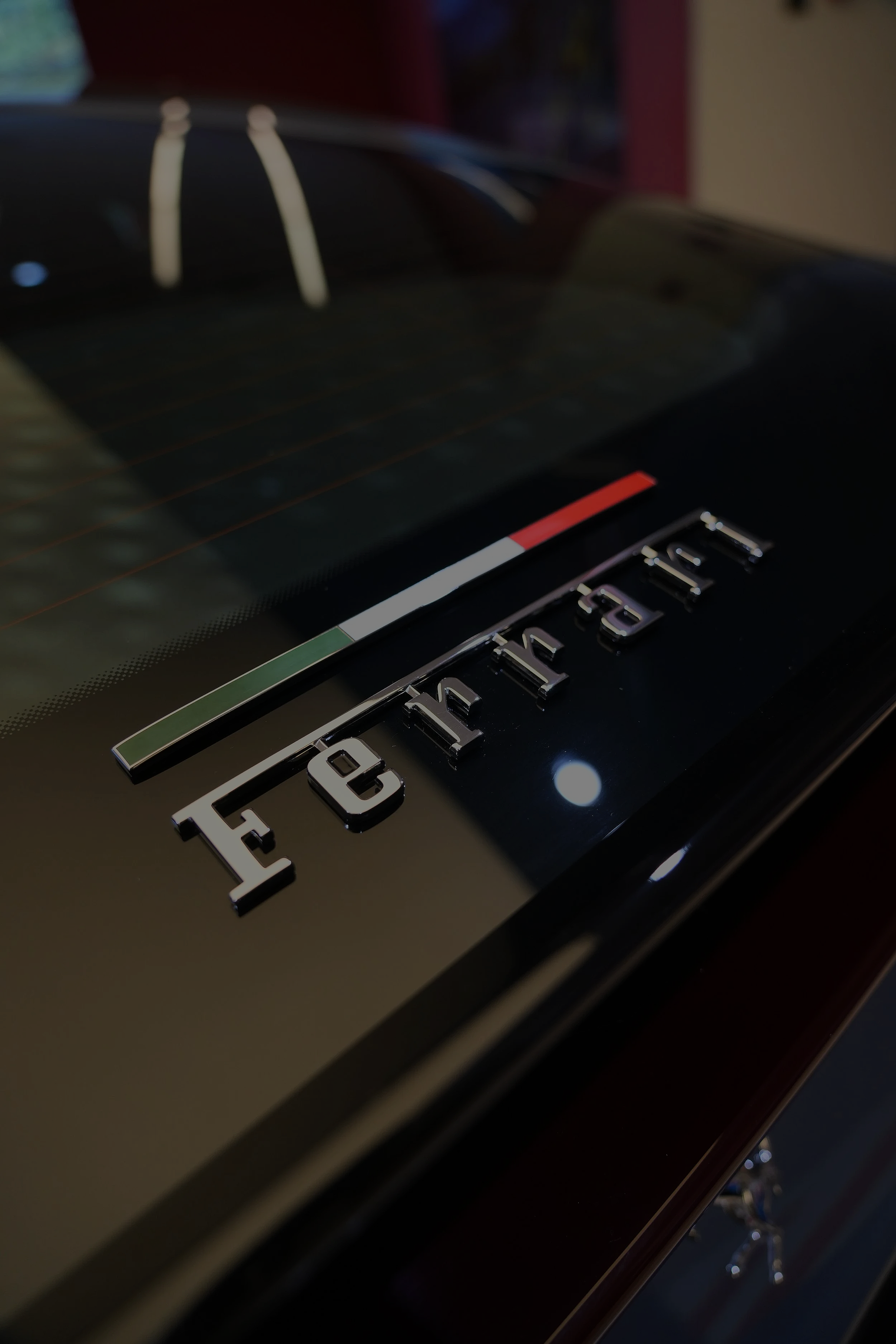 Close-up of a black Ferrari car with silver lettering and the Italian flag stripe.