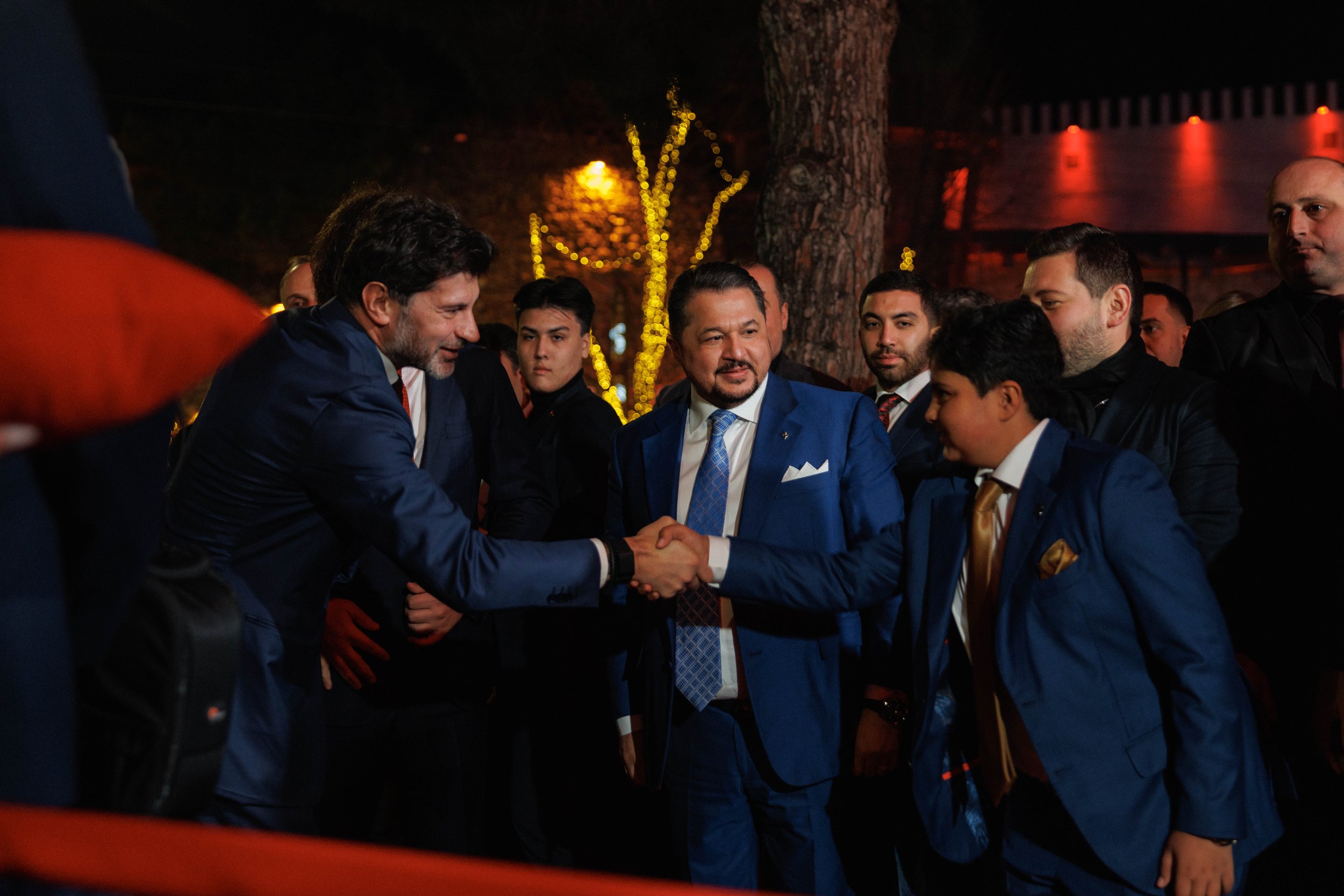 Modern Bugatti showroom with fabric swatches and color samples on a display wall, brown and black leather sofas, and a white marble table.