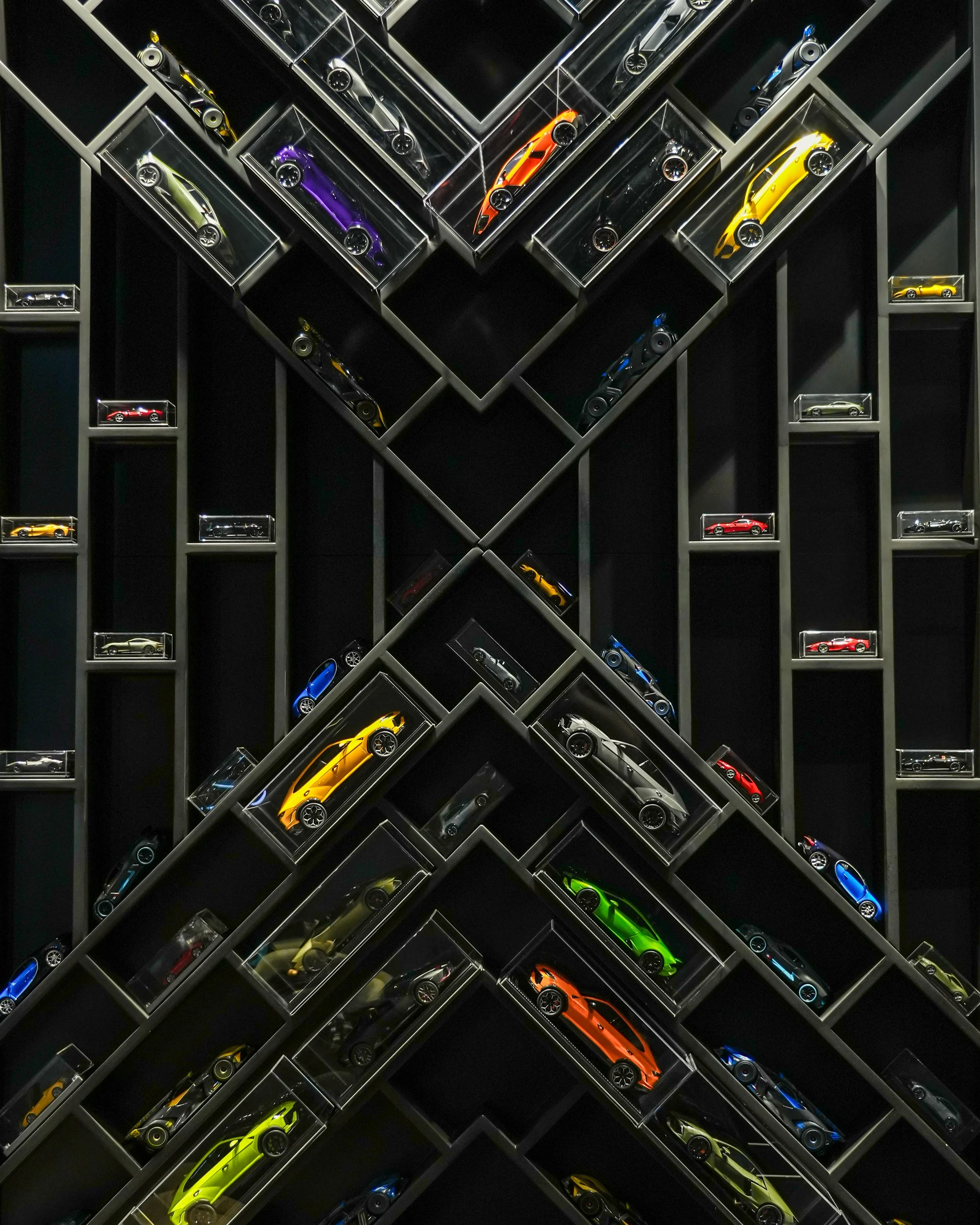 A wall display of miniature cars in glass cases arranged in a geometric pattern.