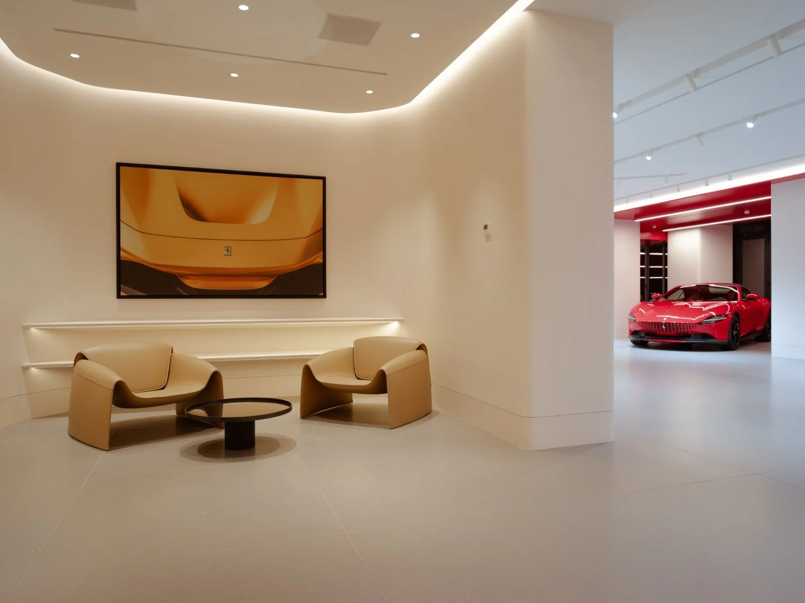 A modern, minimalistic interior space with two beige chairs and a small round black table between them, positioned against a white wall with a large abstract artwork. To the right, through an opening, a red luxury sports car is parked in a sleek, well-lit showroom.