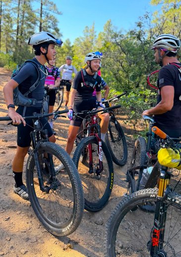 Two BEYOND Racing riders standing with their bikes on a wooded trail.