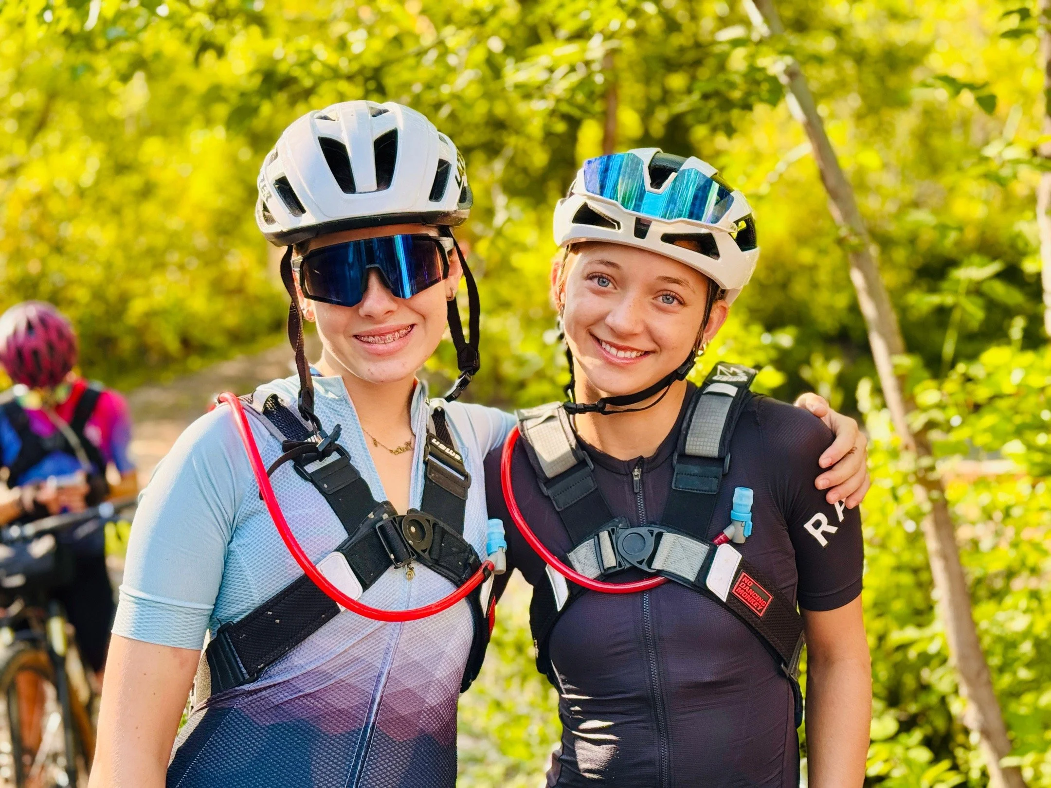 Two Beyond Racing riders in helmets smiling together after a ride.