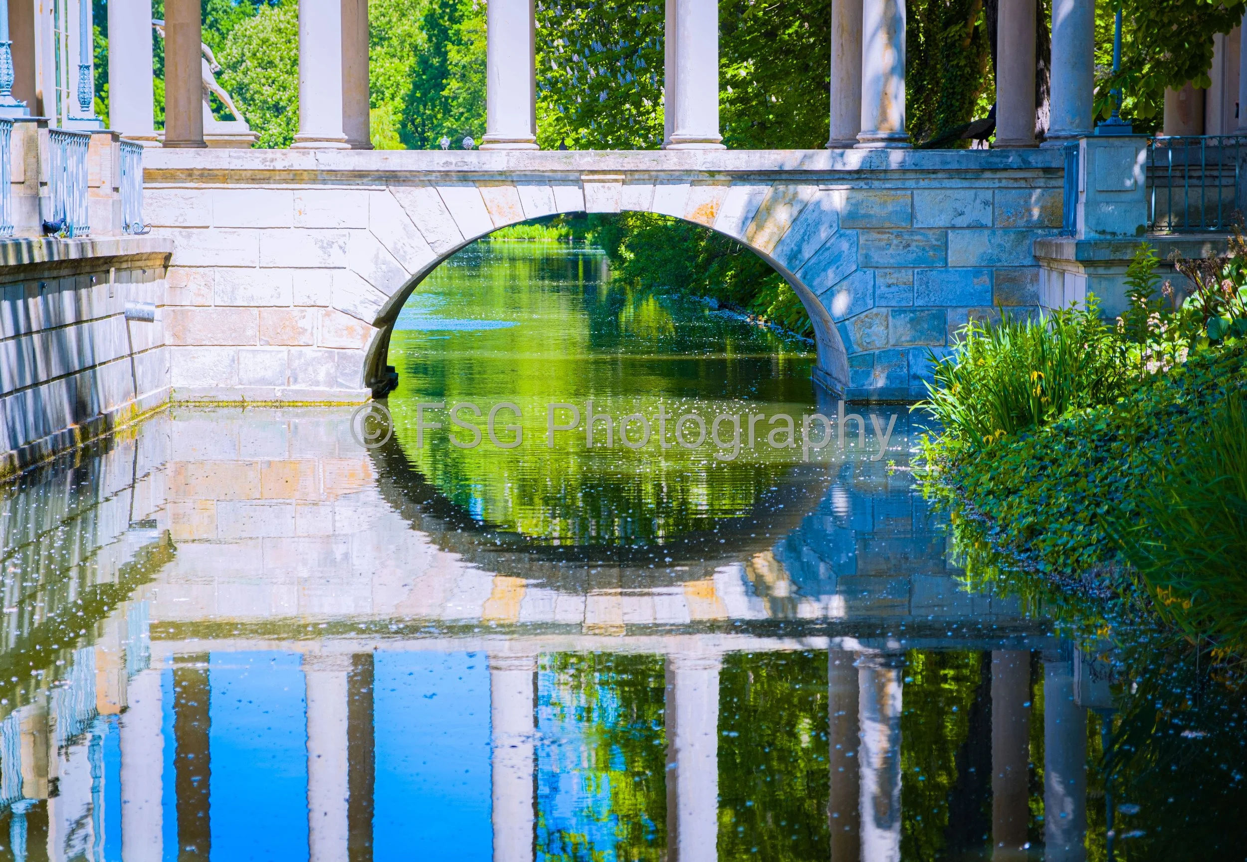 Inverted Sanctuary

This piece captures a mesmerizing interplay of stone, water, and light. The vertical symmetry of the surrounding stone columns draws the eye directly towards the central moongate, which frames a vibrant, textured explosion of sunl