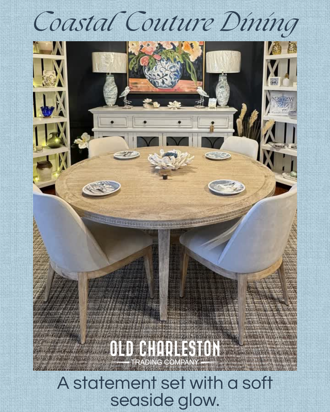 A coastal-themed dining room with a round wooden table set with four decorative plates and a centerpiece. Surrounding the table are four white upholstered chairs. In the background, a sideboard with lamps, art, and decorative items is flanked by white shelves, creating a coastal decor style.