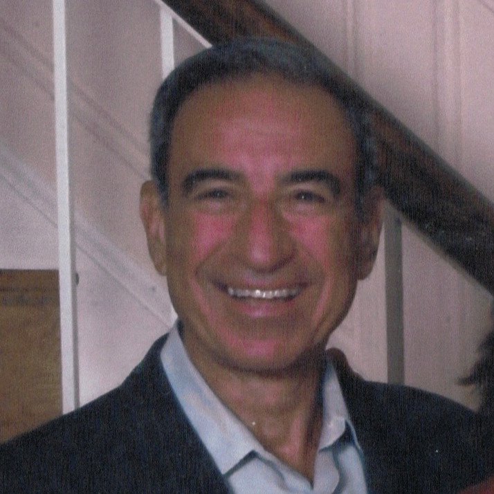 A smiling Backstory client, middle-aged man with short dark hair, wearing a suit jacket and collared shirt.