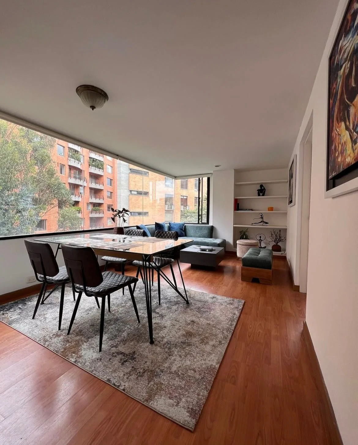 Entrada de edificio de ladrillos con escaleras y barandillas negras, con plantas en las ventanas y el letrero 'El mirador' en la pared.