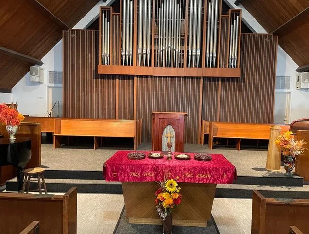 The pulpit with fall flowers and the pipe organ behind it, in the chapel where Oceanside URC worships