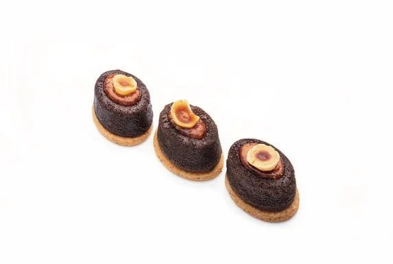 Three mini chocolate fondants with a dark chocolate shell and a hazelnut topping