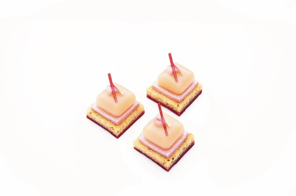 Three layered litchi and rose petits fours in pink and cream tiers on picks