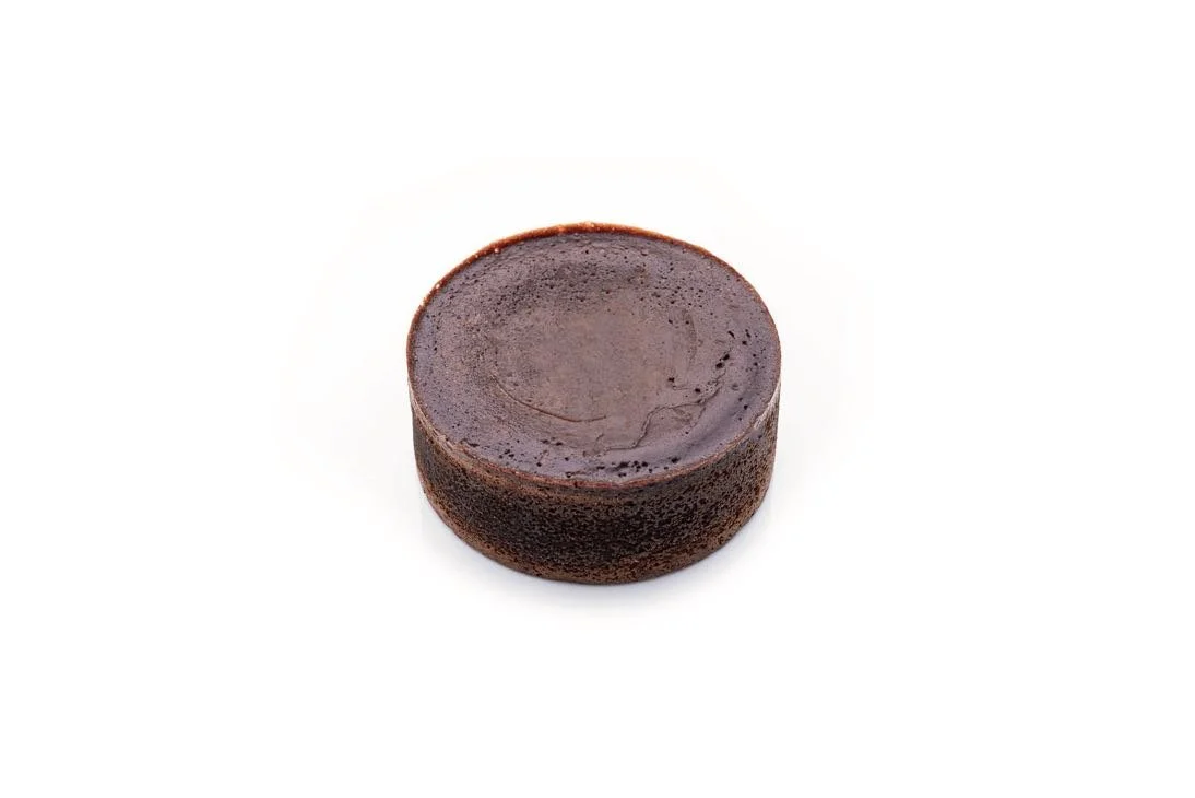 Round chocolate fondant lava cake with a smooth dark top, photographed on a white background