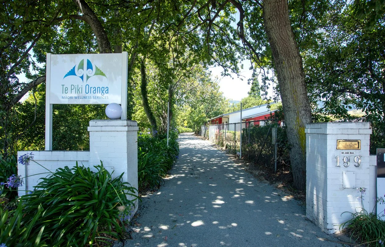 Exterior view of the Te Piki Oranga Whakatū Hauora Hub, featuring a tree-lined driveway and Te Piki Oranga signage