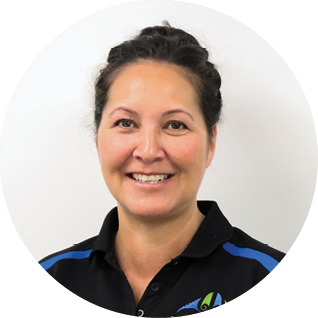 A woman with dark hair pulled back, smiling, wearing a black polo shirt with blue accents and a logo on the left side.