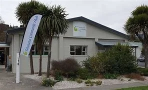 Building with a sign that says 'Coastal Chiropractic,' surrounded by palm trees and bushes under a cloudy sky.