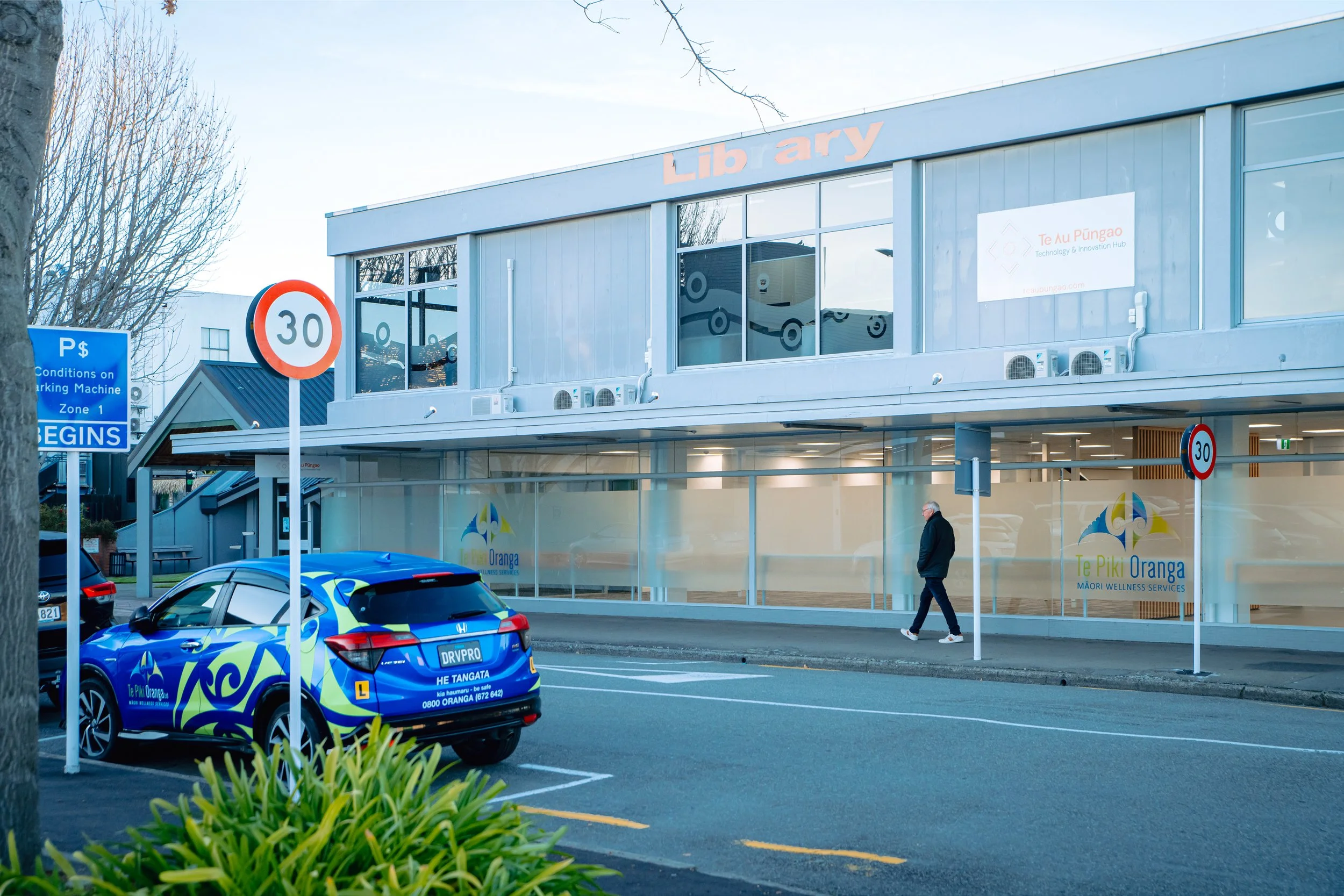 Exterior view of a healthcare facility named CIVIC FAMILY HEALTH CARE with glass doors, parked cars, and scooters in front.