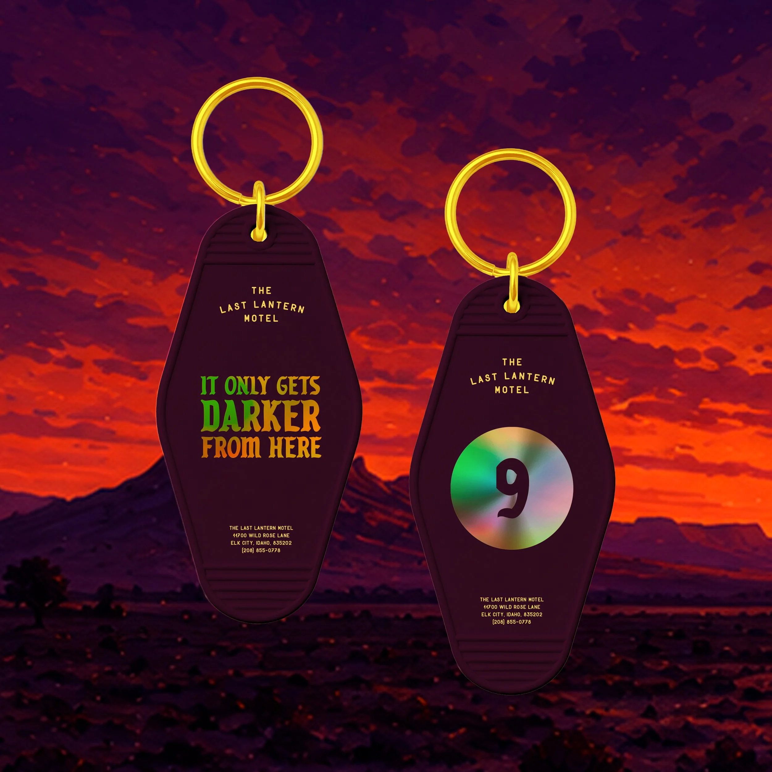 Yellow keychain with black tag that says 'The Last Lantern Motel,' displaying address and phone number, against a red and black textured background.