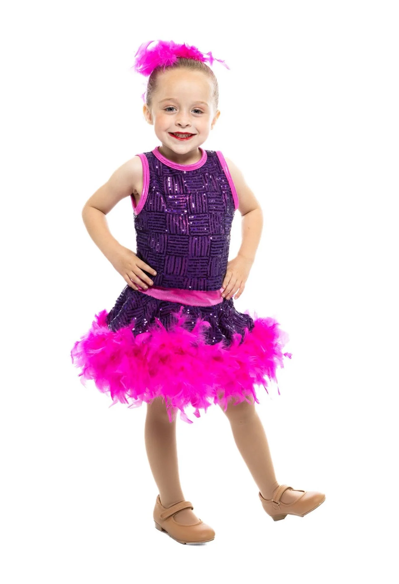 Young girl in purple sequined dress with pink feather trim, pink feather headband, and tan tap shoes, smiling and posing with hands on hips.