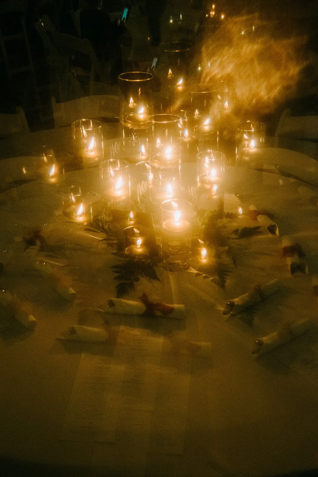 Table with multiple lit candles, surrounded by fish-shaped decorations, in a dimly lit setting.