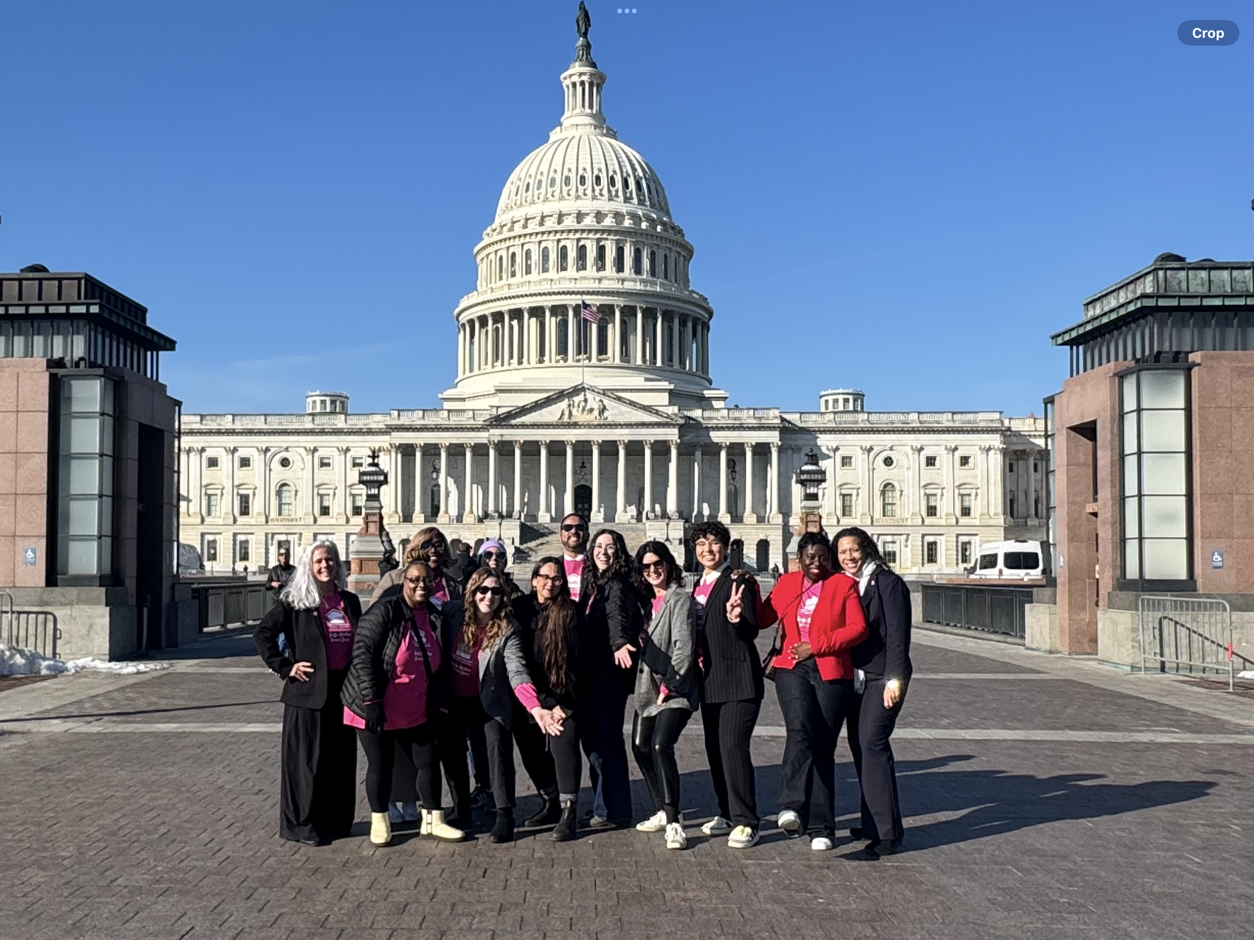 Group of people standing in front of the U.S. Capitol building in Washington, D.C., on a sunny day.