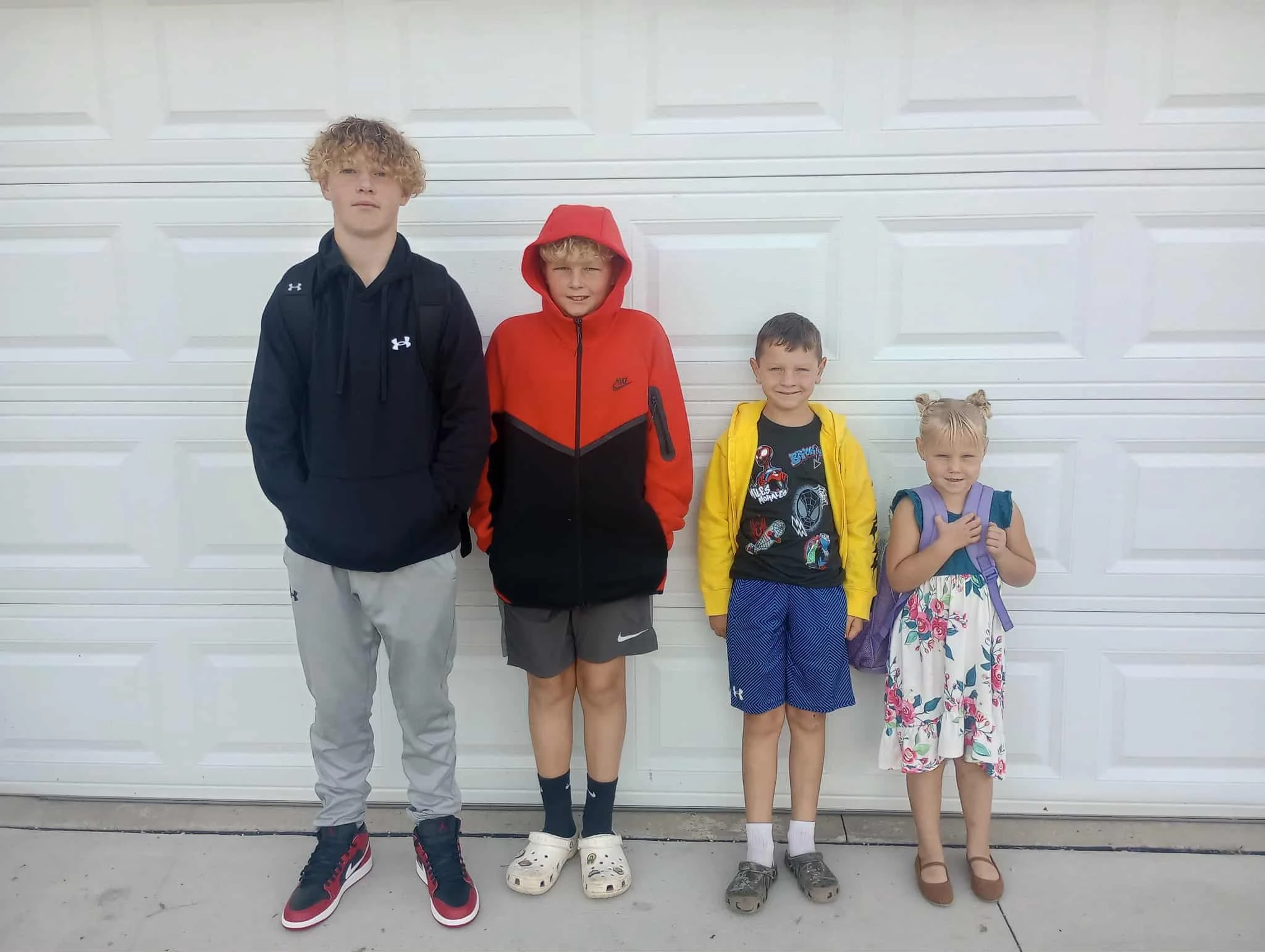 Four children standing in front of a white garage door