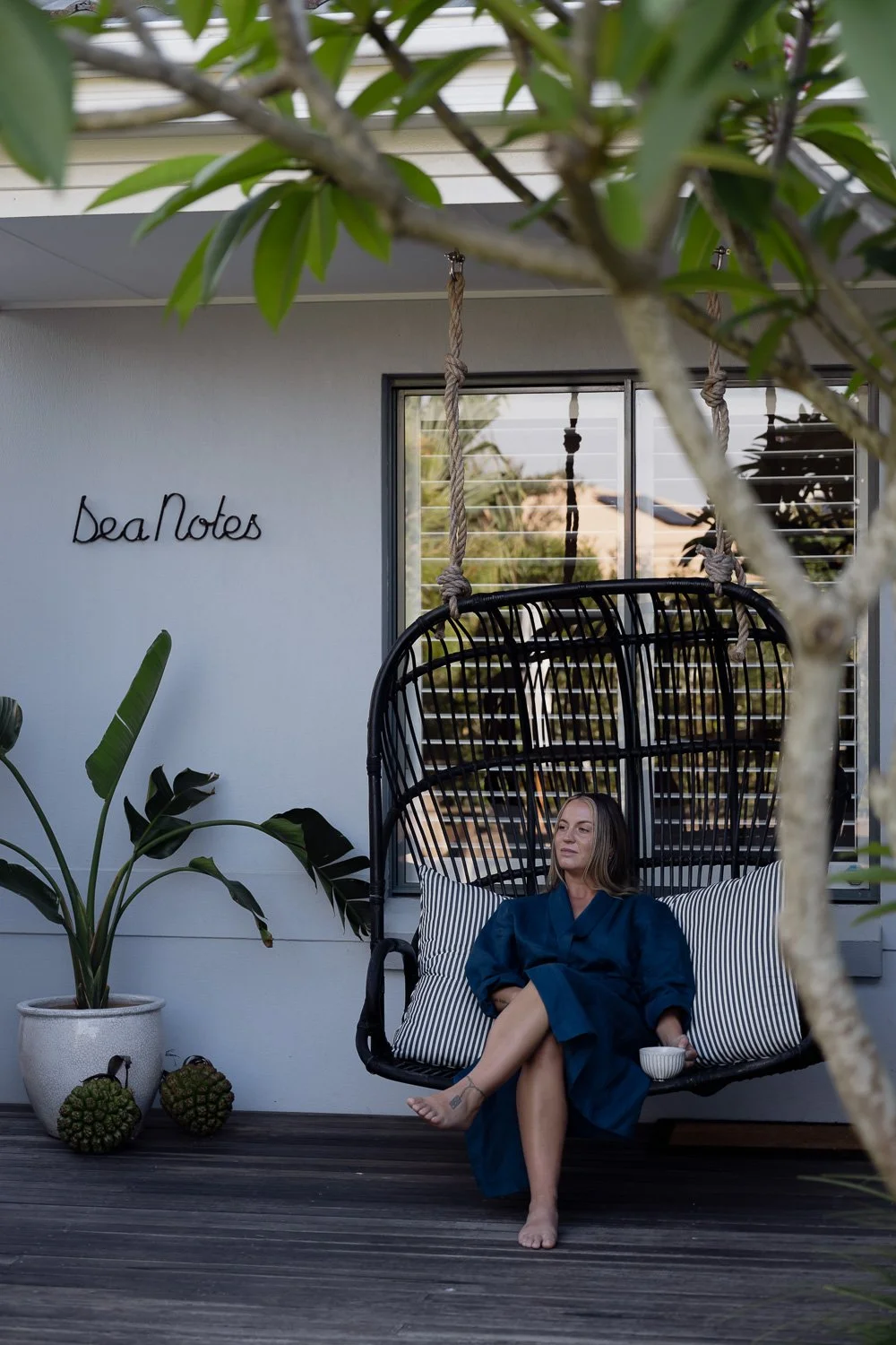 Female guest enjoying a cup of tea on the outdoor hanging chair 
