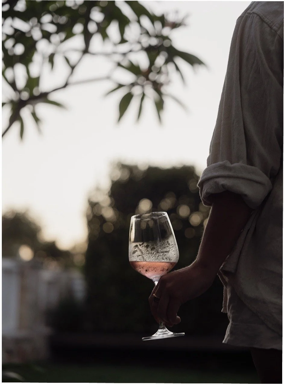 Guest holding a glass of chilled rose wine at dusk in the garden