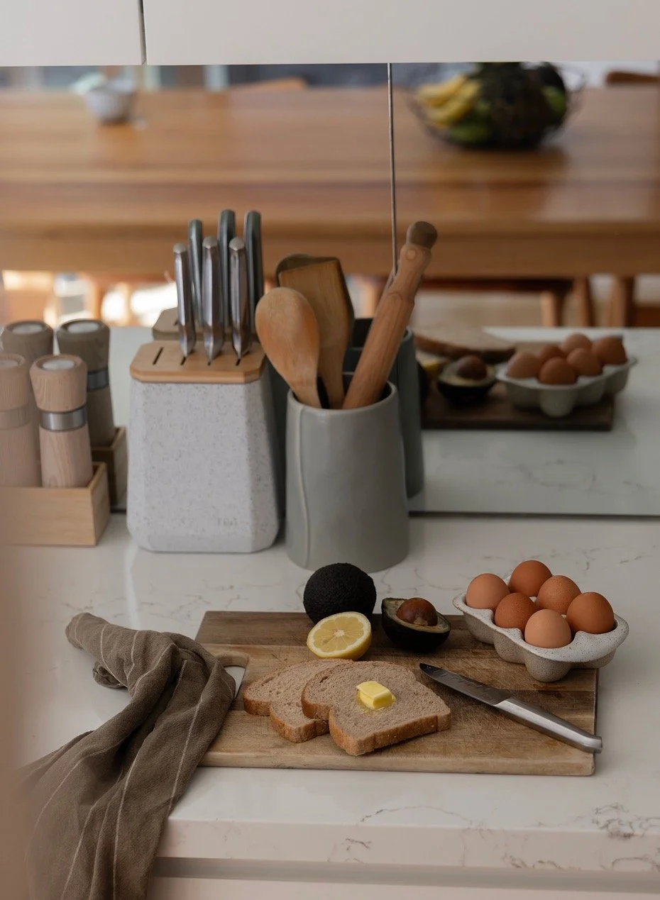 Eggs, avocado and sliced sourdough on stone kitchen benchtop