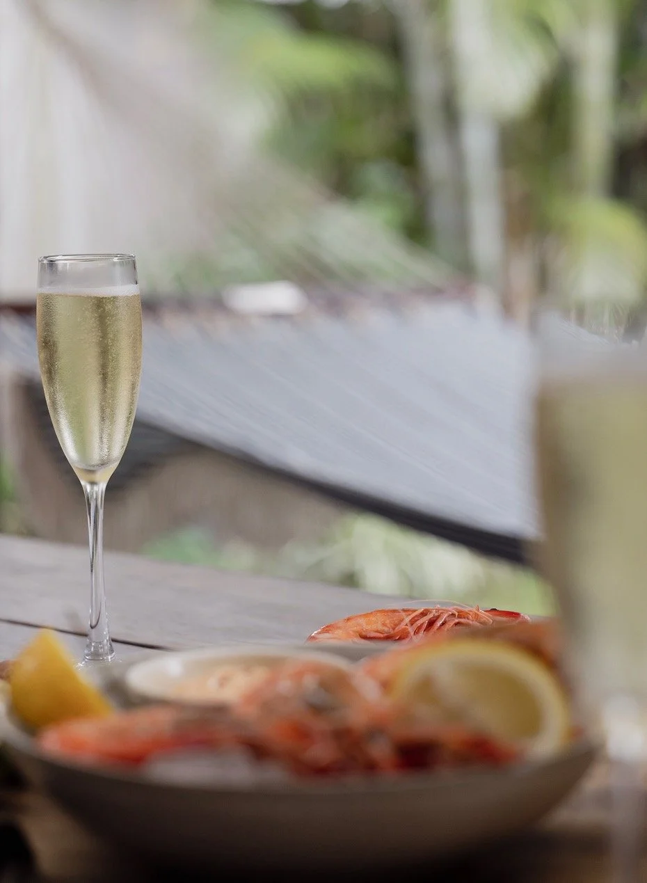 Yamba prawns, lemon wedges, and two glasses of bubbles on outdoor dining table