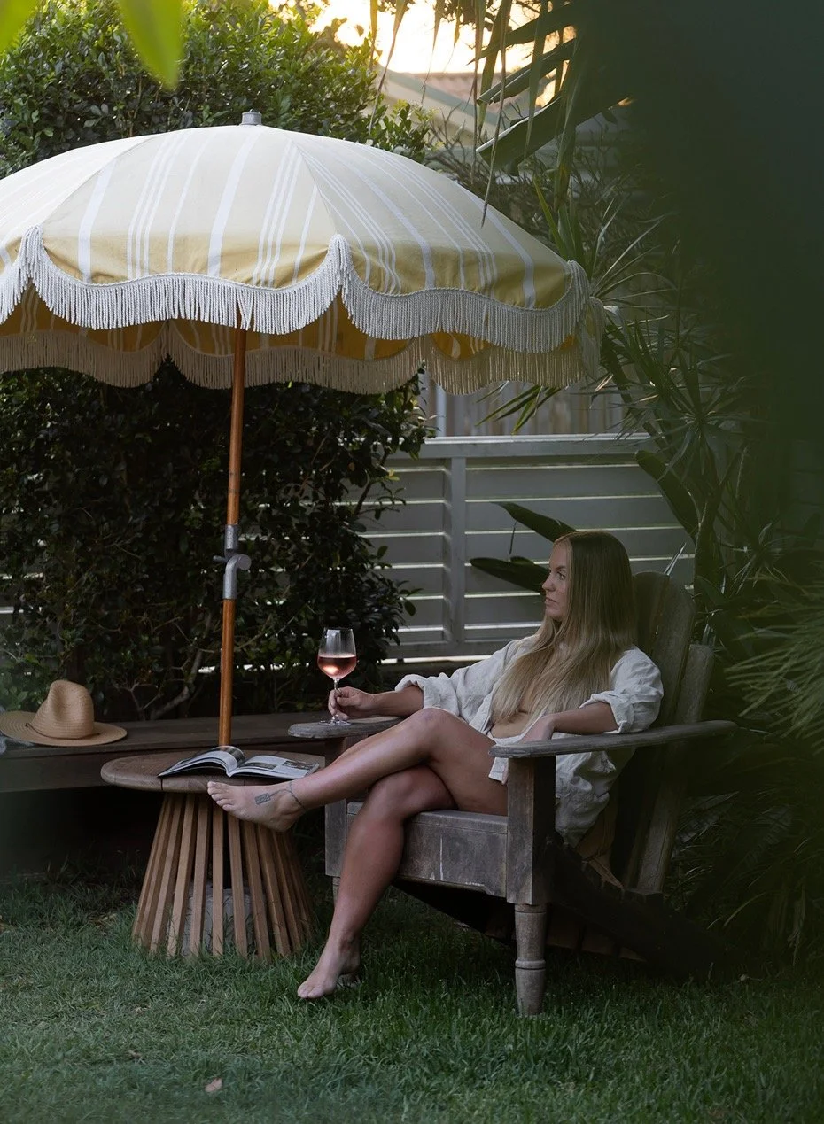 female guest enjoying a quiet wine beneath the garden umbrella