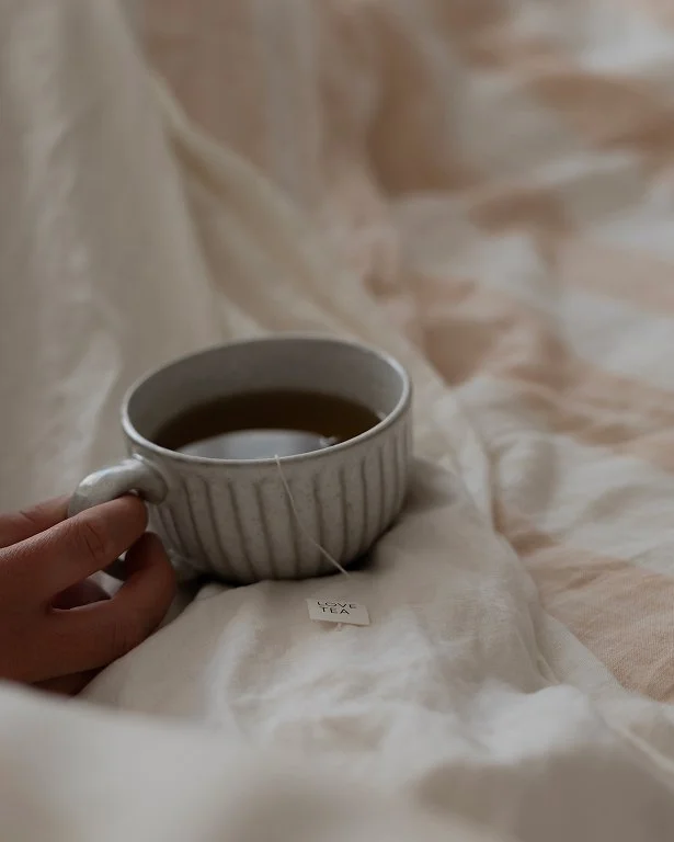 Female holding a teacup in bed