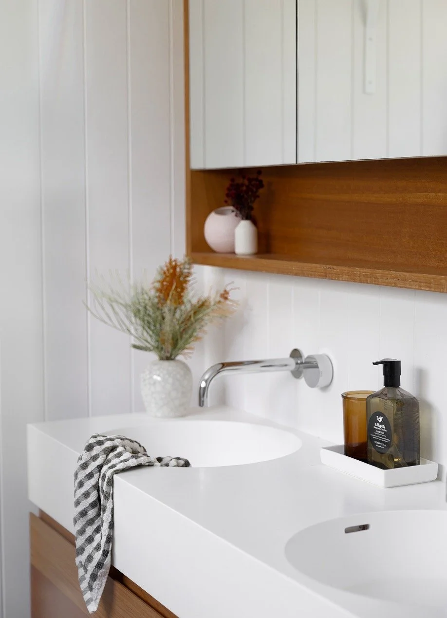 Modern whote double vanity and sinks with fresh banksia in a vase