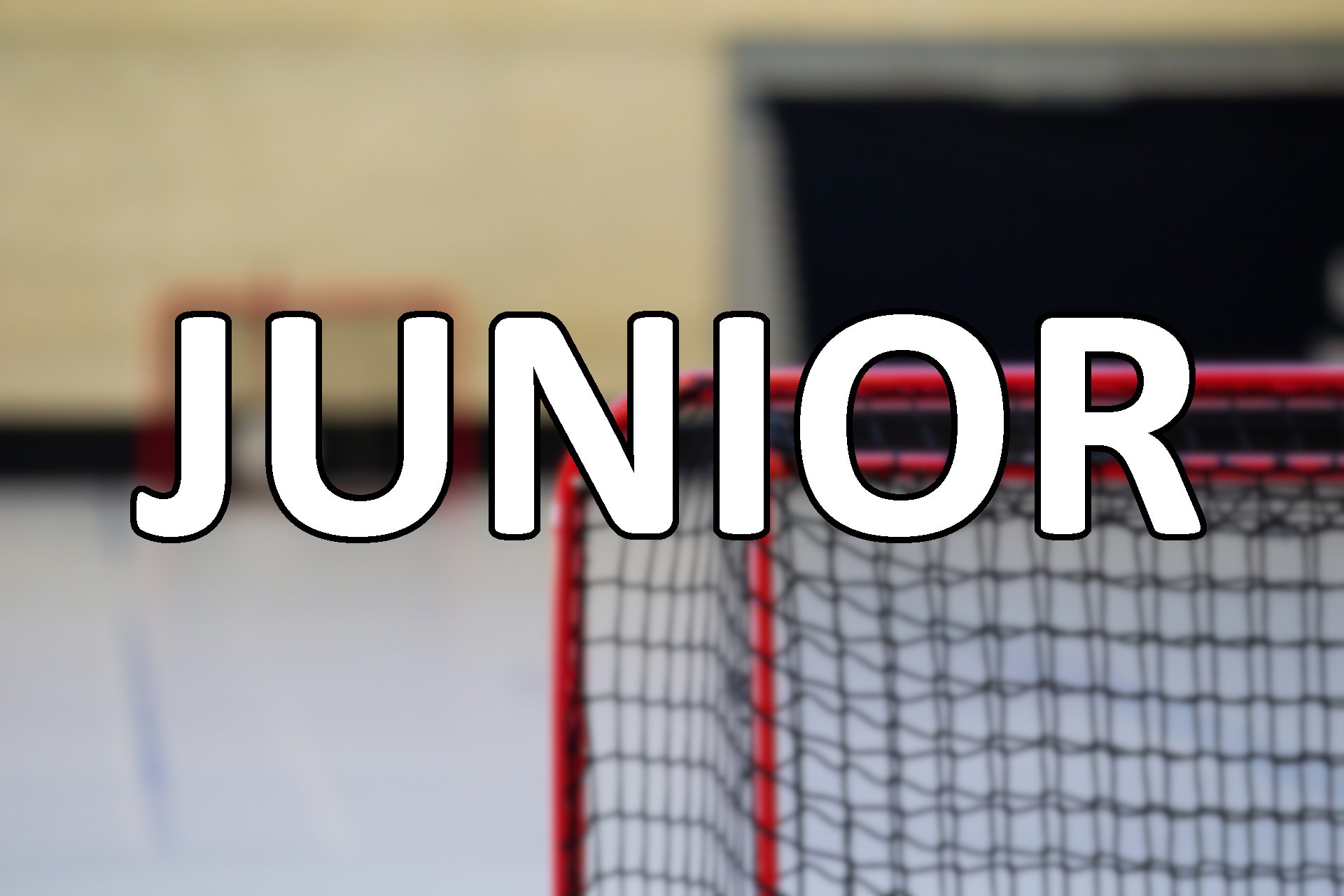 Close-up of a mini hockey goal with a sign reading 'JUNIOR' in front of it, on an indoor hockey rink.