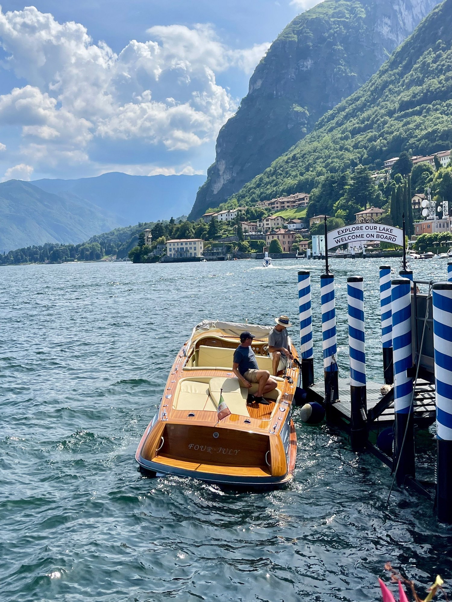 A wooden motorboat on the blue water of Lake Como below green mountains